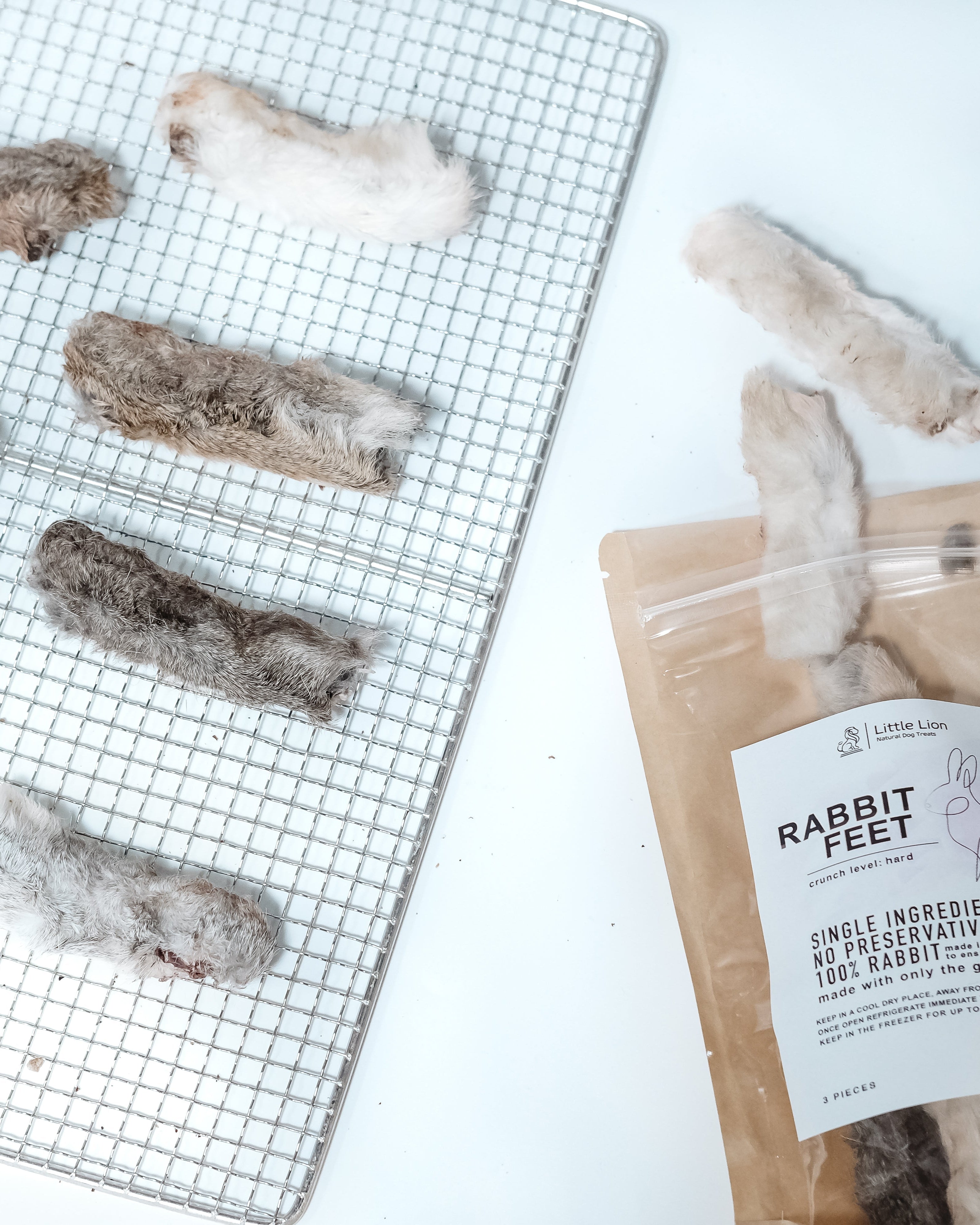 Dried rabbit feet on a cooling rack with a package labeled 'Rabbit Feet' on a white background.