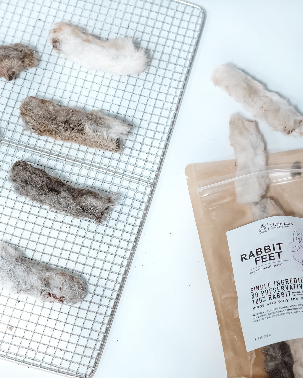 Dried rabbit feet on a cooling rack with a package labeled 'Rabbit Feet' on a white background.